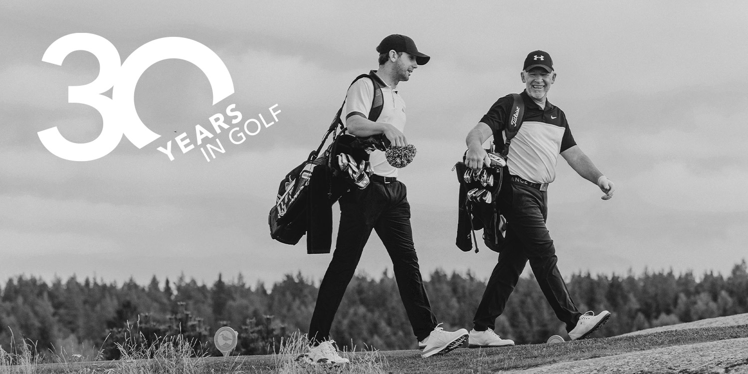 Två golfare går med golfbagar på en bana, leende mot varandra. Text: "30 Years in Golf" syns i hörnet.