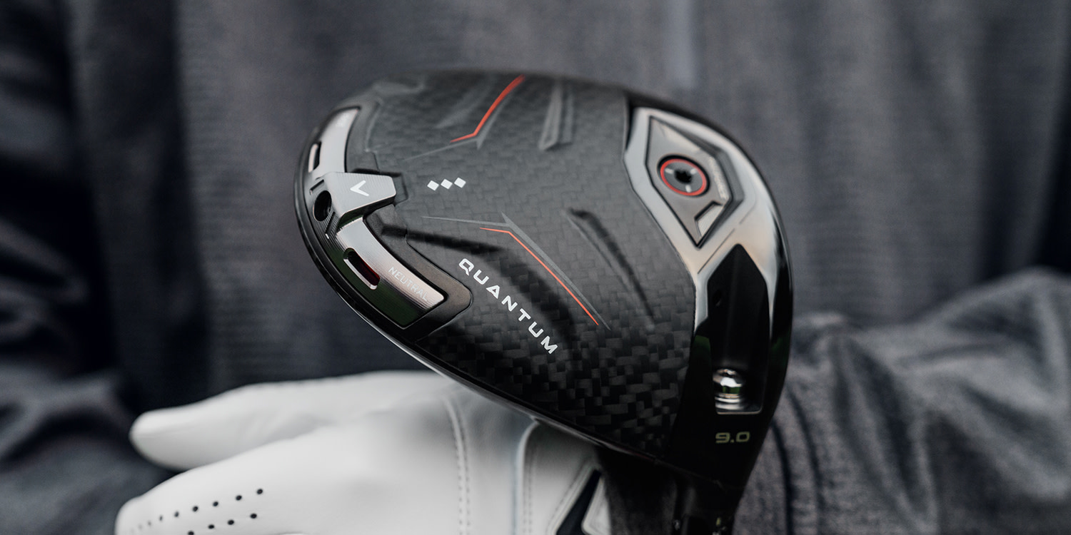 Golfari, jolla on valkoinen hanska, pitää kädessään mustaa golfmailan päätä, jossa lukee "QUANTUM" ja "NEUTRAL" tumman taustan edessä.