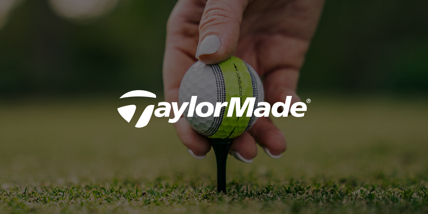 Logo: TaylorMade-tekst over en hånd, der placerer en golfbold på en tee på græsset.