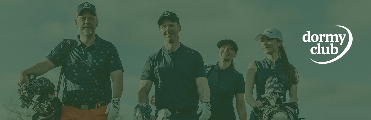 Fyra personer går tillsammans på en golfbana, bärande golfbagar och klädda i golfkläder under en klar himmel.