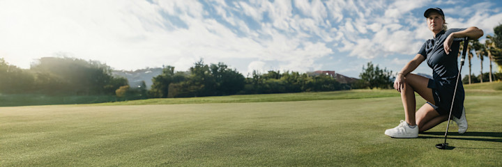Kaksi naista kävelee ja juttelee yhdessä golfkentällä, molemmilla yllään urheiluvaatteet ja he pitävät golfmailoja käsissään.