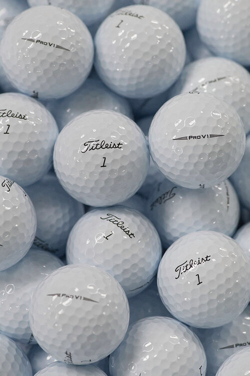 Flera vita Titleist Pro V1 golfbollar med siffran 1 staplade tillsammans i en hög.