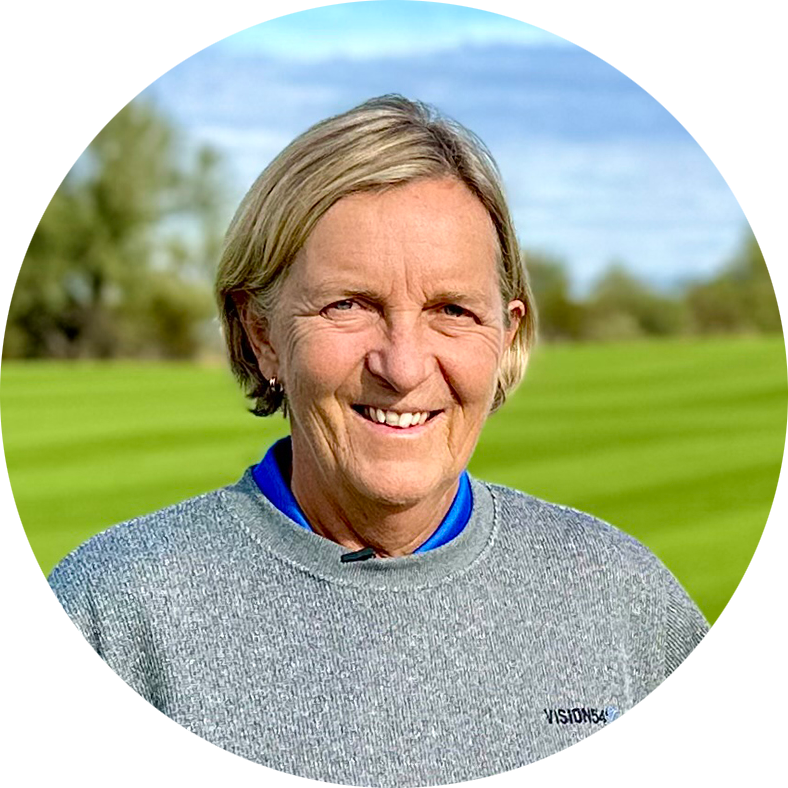 Leende kvinna med blont hår bär grå tröja och står utomhus på en grön gräsmatta med träd i bakgrunden.