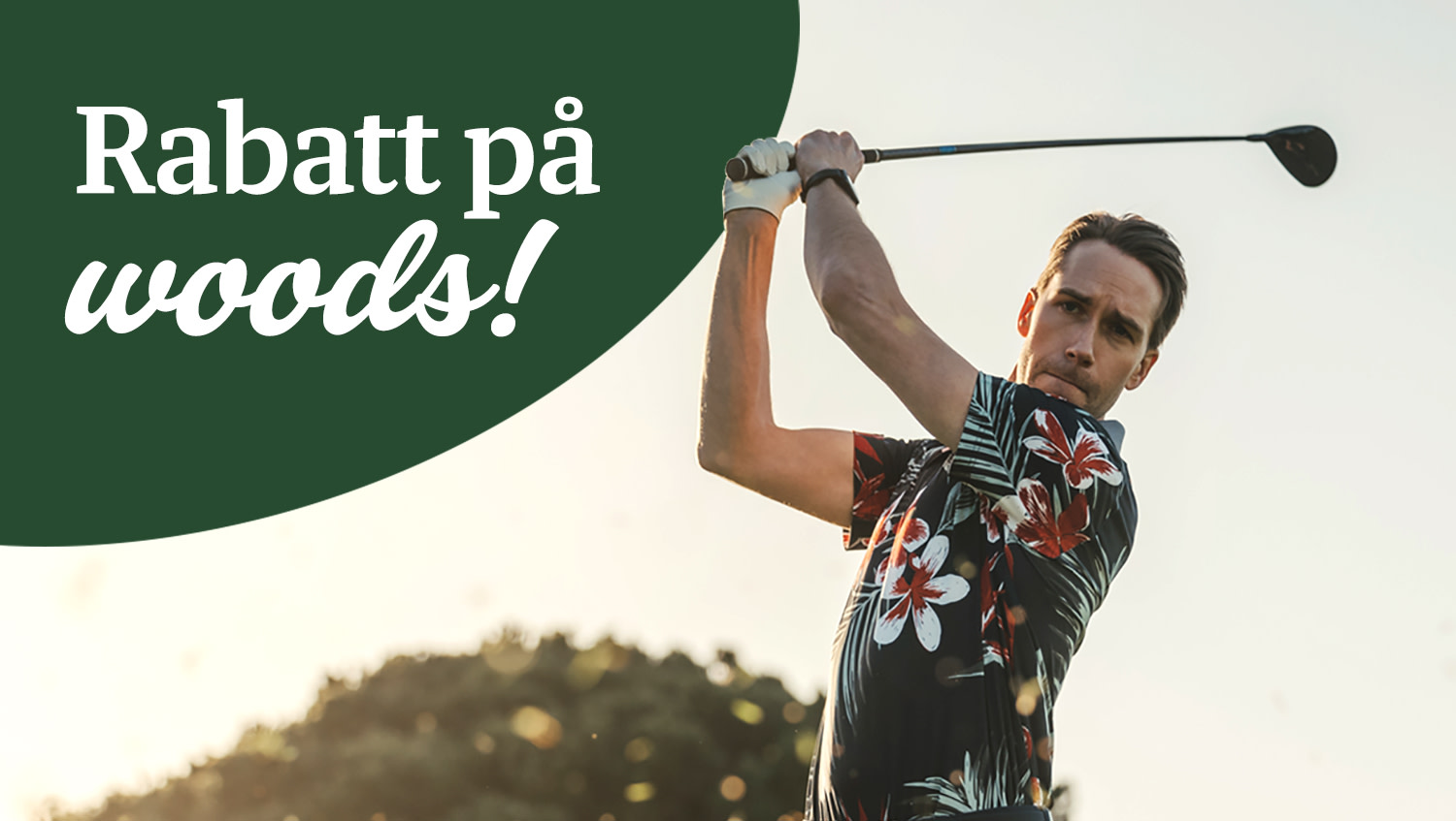 Man svingar en golfklubba utomhus, bär blommig skjorta och golfhandske, med solnedgång i bakgrunden.