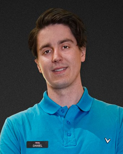 Man i blå pikétröja med namnbricka som det står "Daniel" på, står framför en mörk bakgrund och ler lätt.