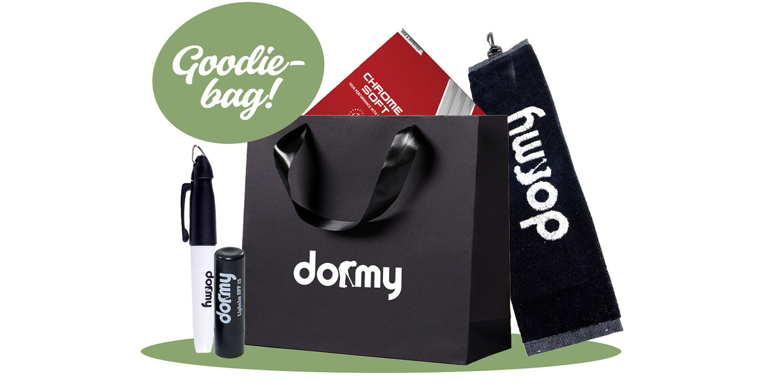 Svart goodiebag med Dormy-logga, innehållande penna, läppbalsam, golfhandduk och golfbollar, samt texten "Goodie-bag!".