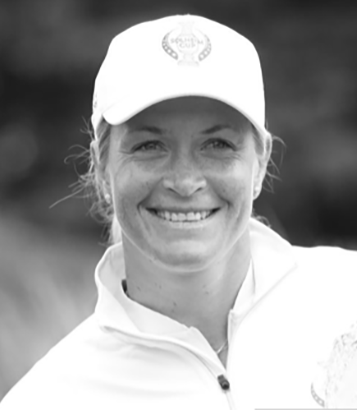 Kvinna med keps och dragkedjetröja ler utomhus, suddig bakgrund.