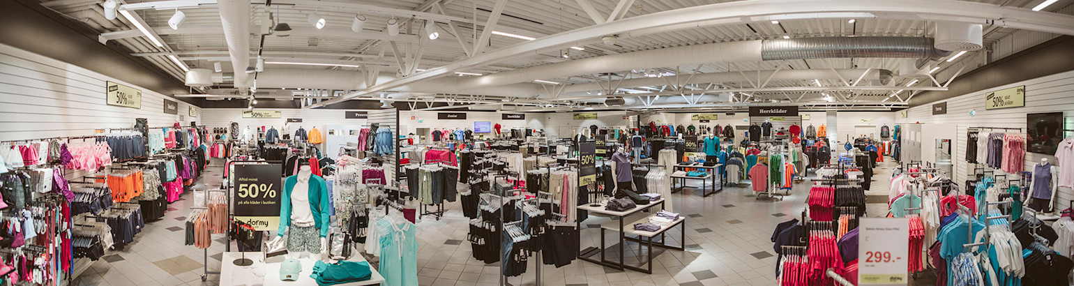 Klädbutik med välorganiserade klädställningar, skyltdockor och skyltar som visar "50% rabatt" på utvalda varor.