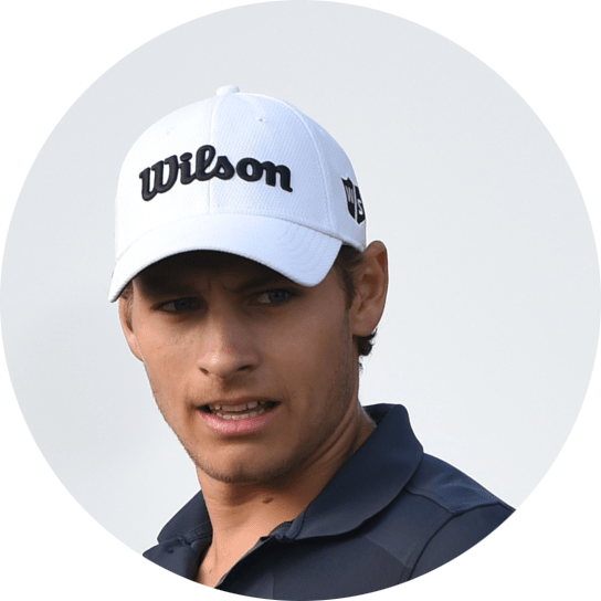 Man med vit keps med texten "Wilson" tittar åt sidan, klädd i mörk pikétröja mot ljus bakgrund.