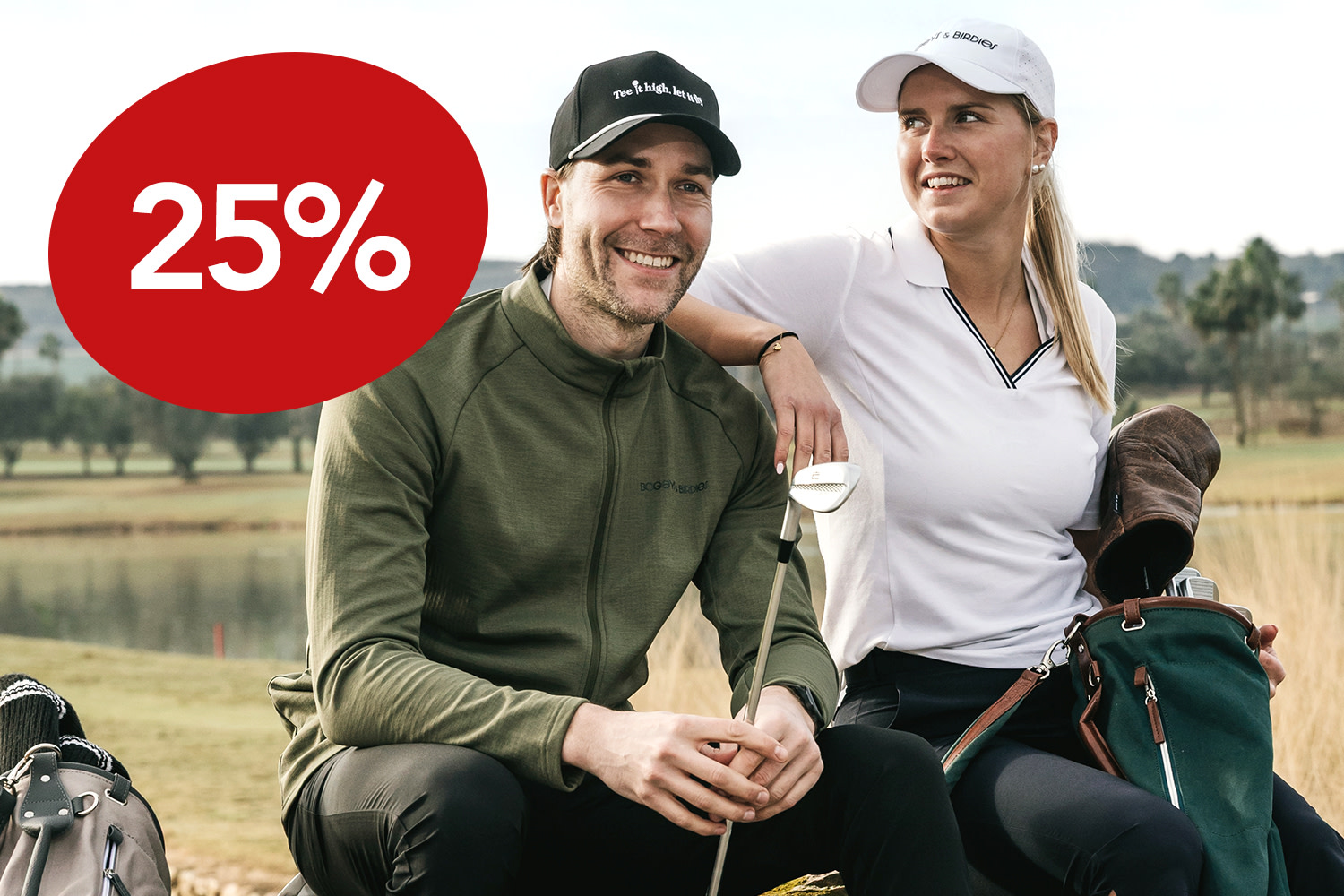 Två golfare går sida vid sida med golfbagar över axeln under en klar blå himmel.
