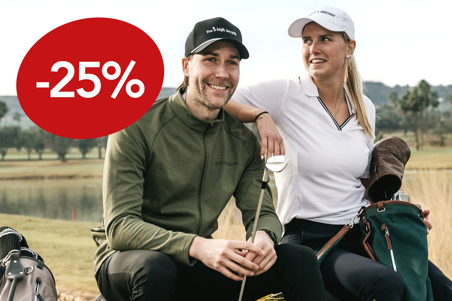 Kaksi golfaria kävelee vierekkäin golfbägit olallaan kirkkaan sinisen taivaan alla.