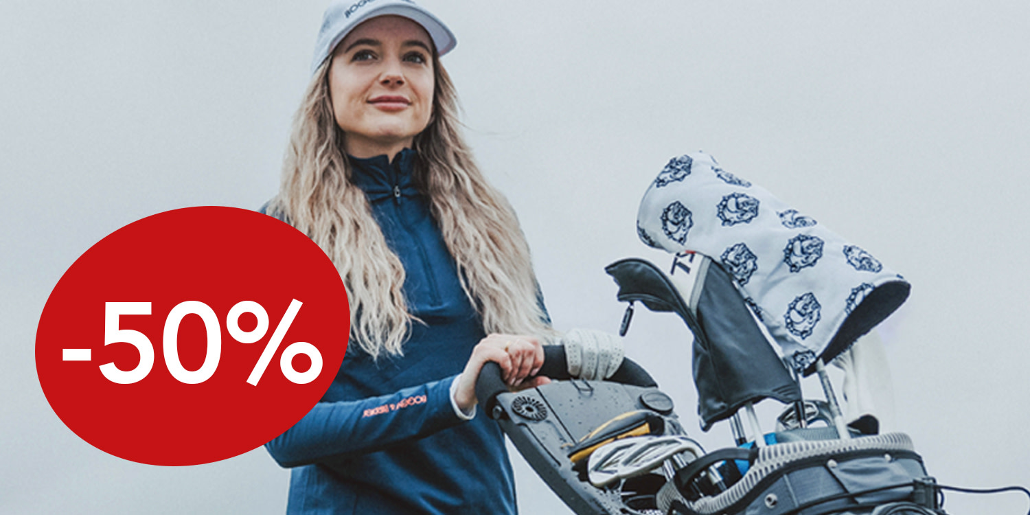 Golfvaatteisiin pukeutunut nainen seisoo golfbägin vieressä, vasemmalla näkyy suuri punainen ympyrä, jossa lukee "50 %".